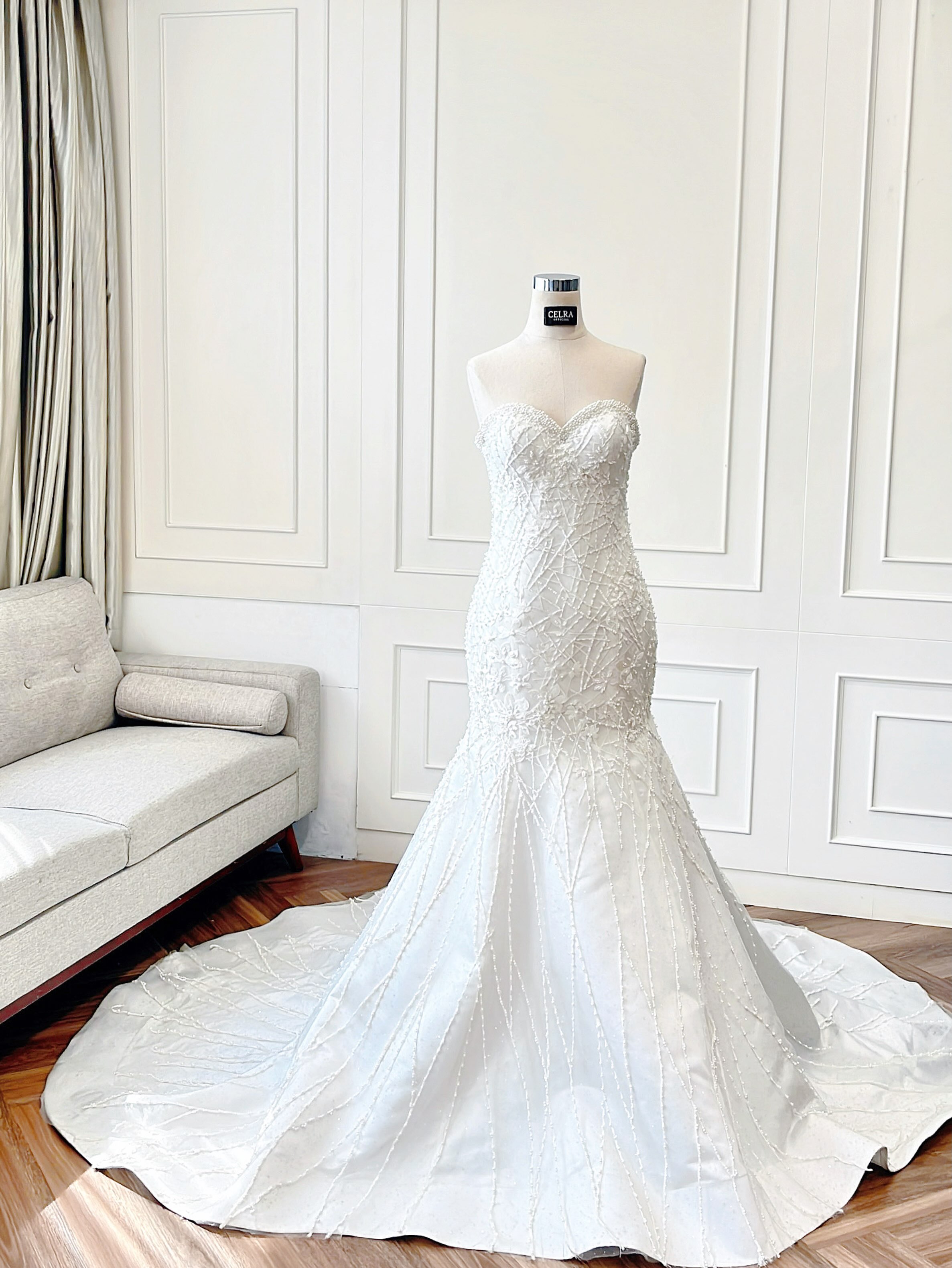 Fitted beaded wedding gown with chapel train on a mannequin by CELRA