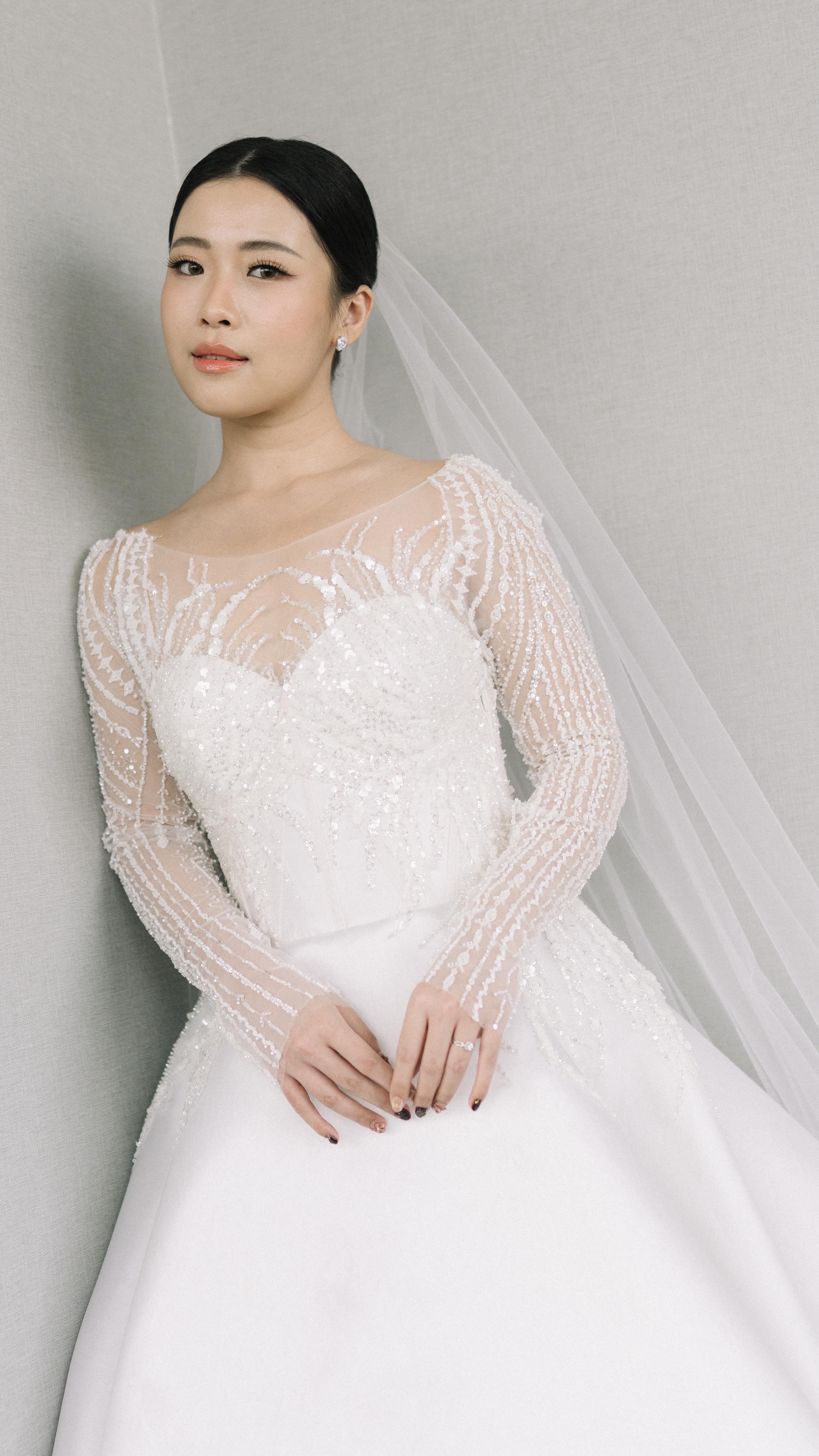 Bride in a long-sleeve beaded lace wedding gown with tulle veil by CELRA
