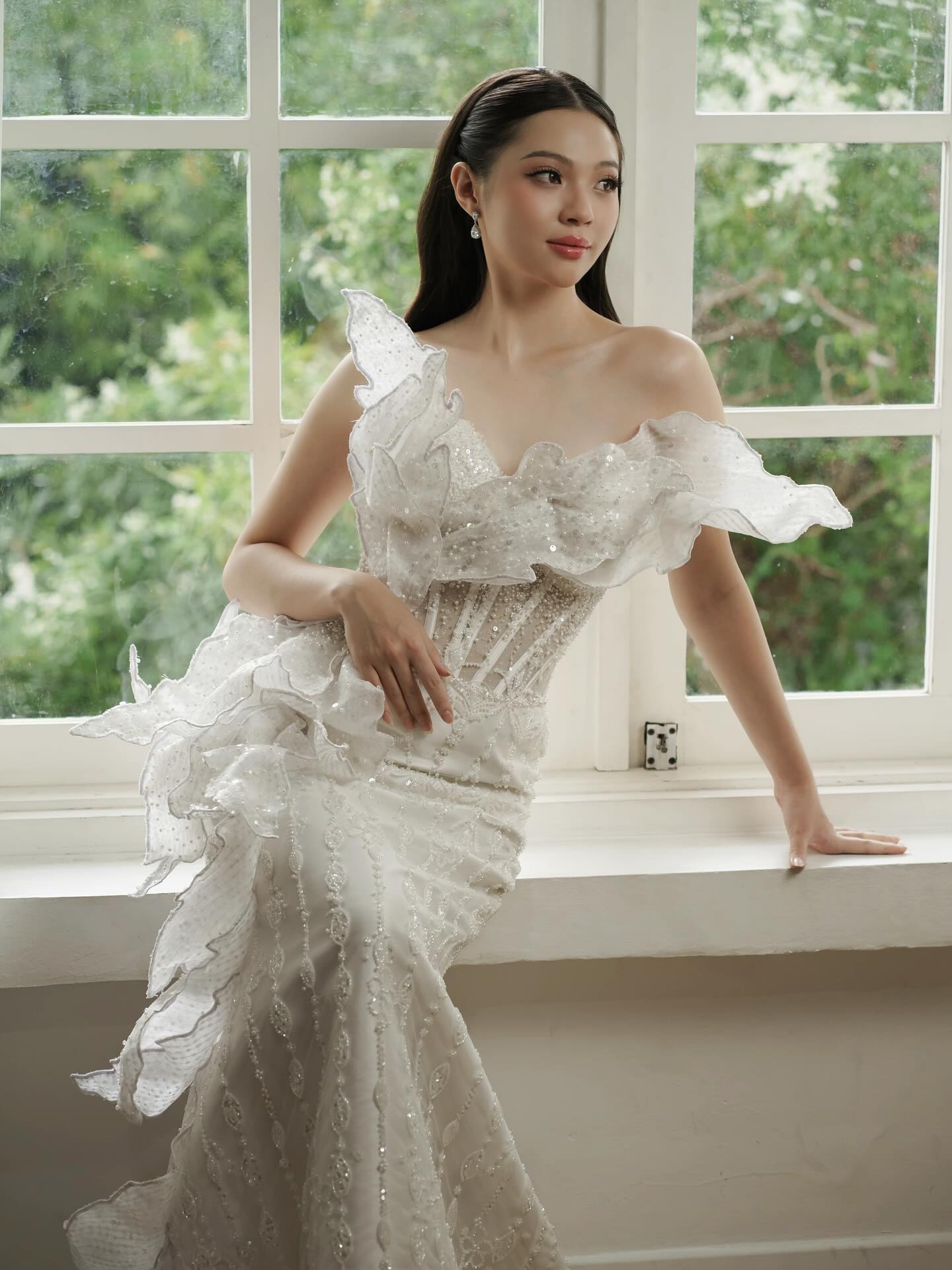 Bride in a sculptural organza ruffle wedding gown at a window by CELRA