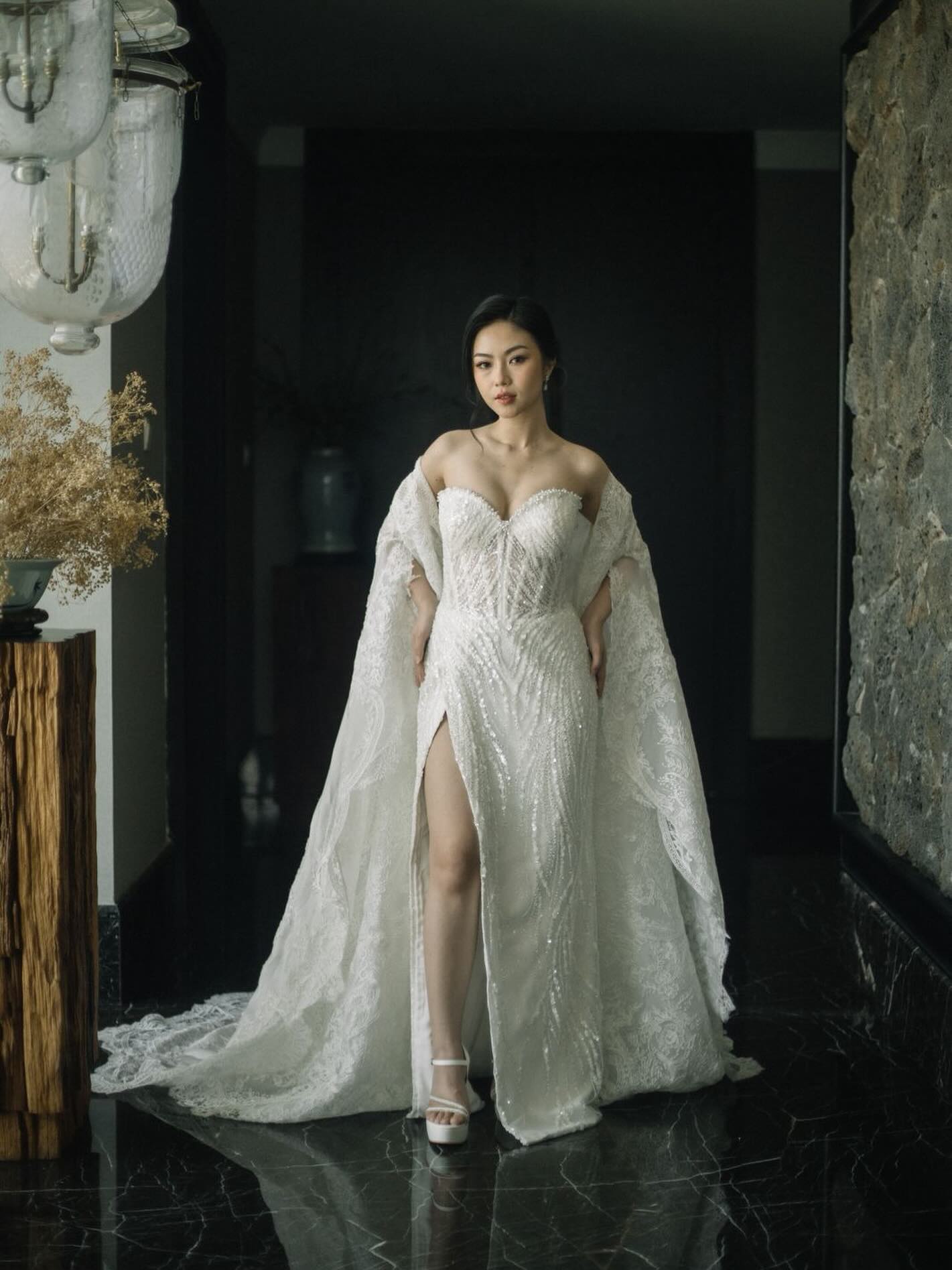 Bride in a beaded gown with lace cape in a marble lobby by CELRA