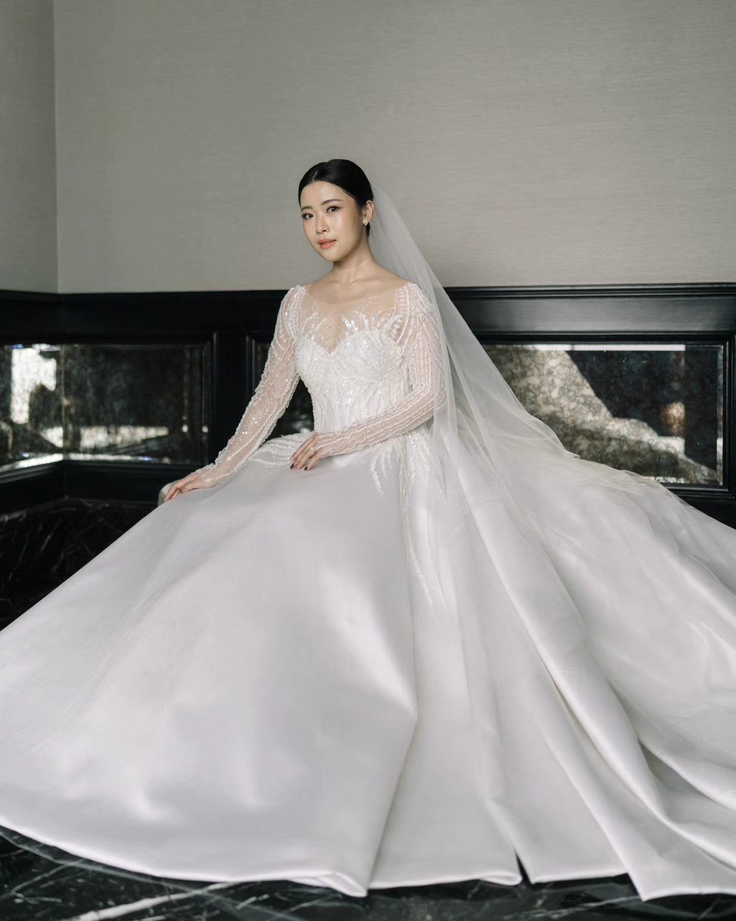Bride seated in a satin ball gown with cathedral veil by CELRA
